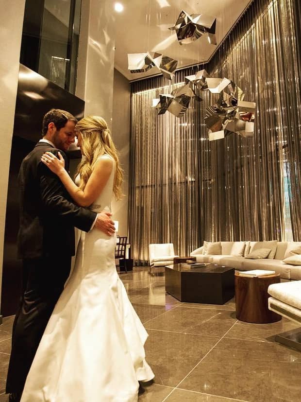 Bride and groom embrace in hotel event space under modern silver sculptures