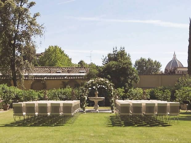 A picturesque garden wedding, featuring rows of chairs facing a fountain and altar amid lush greenery