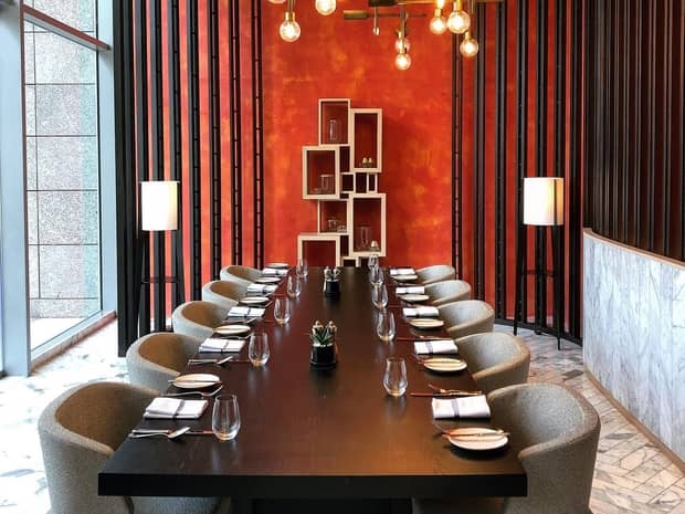 Long modern wood boardroom table with retro style chairs, red accent wall and lights