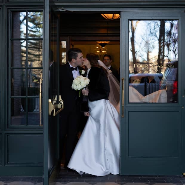 A bride and groom kiss as they stand in a doorway