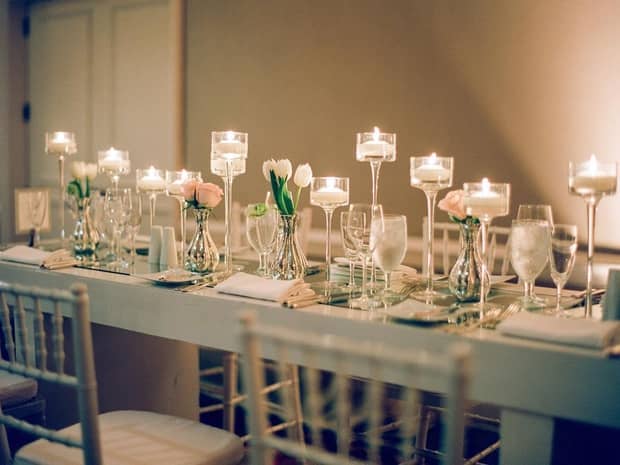 Long wedding dining table set with glassware, candles and white flowers