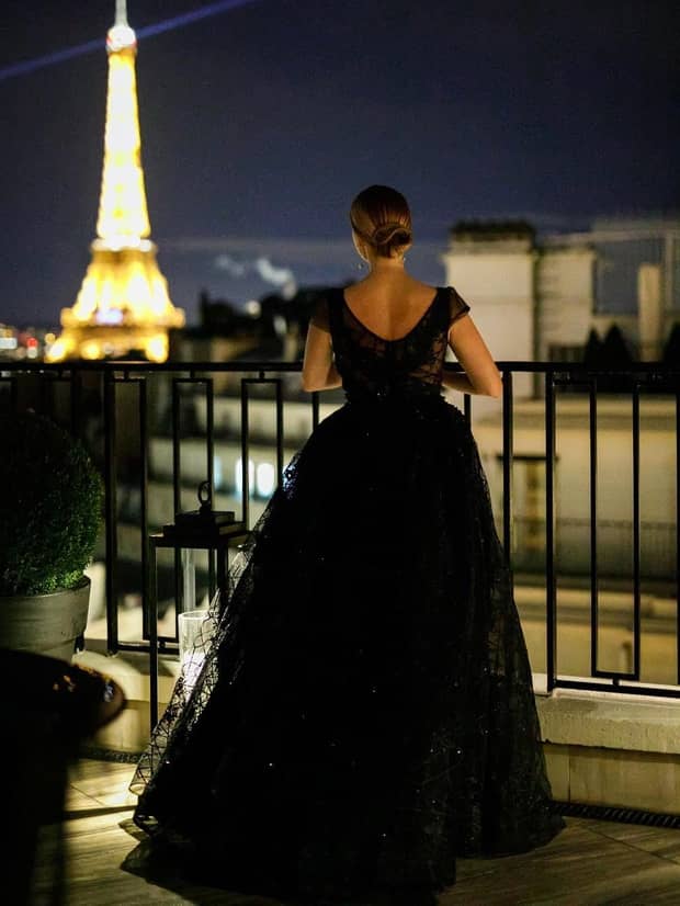 Person in black dress on balcony looking out at Eiffel Tower outside luxury hotel event rooms