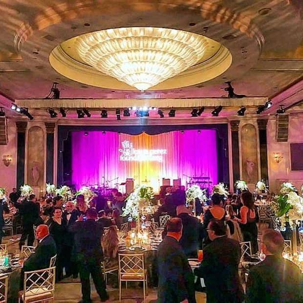 A colourfully lit room during a reception with many people talking and gathering.