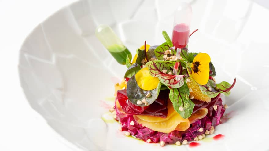 Gourmet chopped beet salad topped with greens, edible flowers