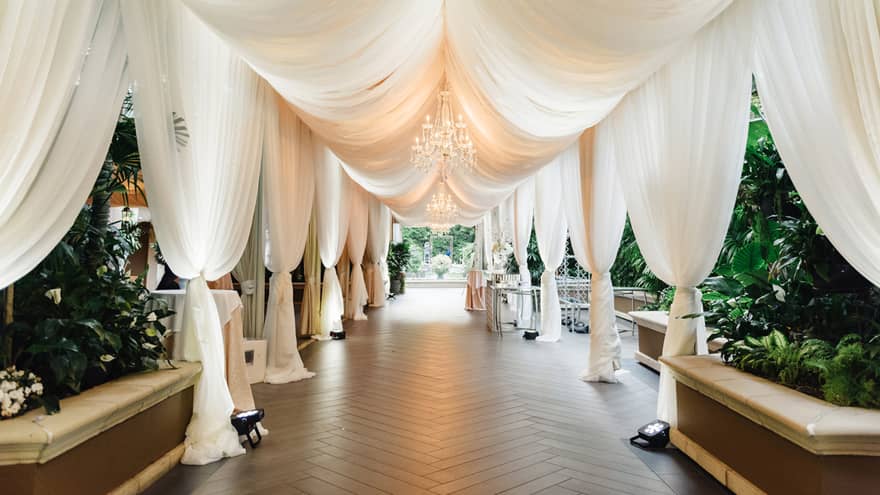White drapes hang over long aisle in outdoor event space