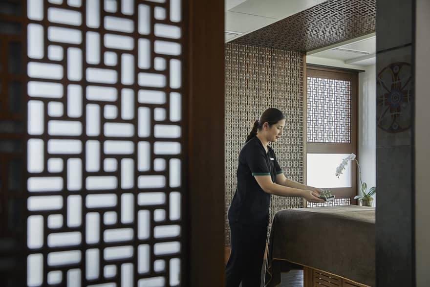 A female esthetician prepares a bed in the massage room. 