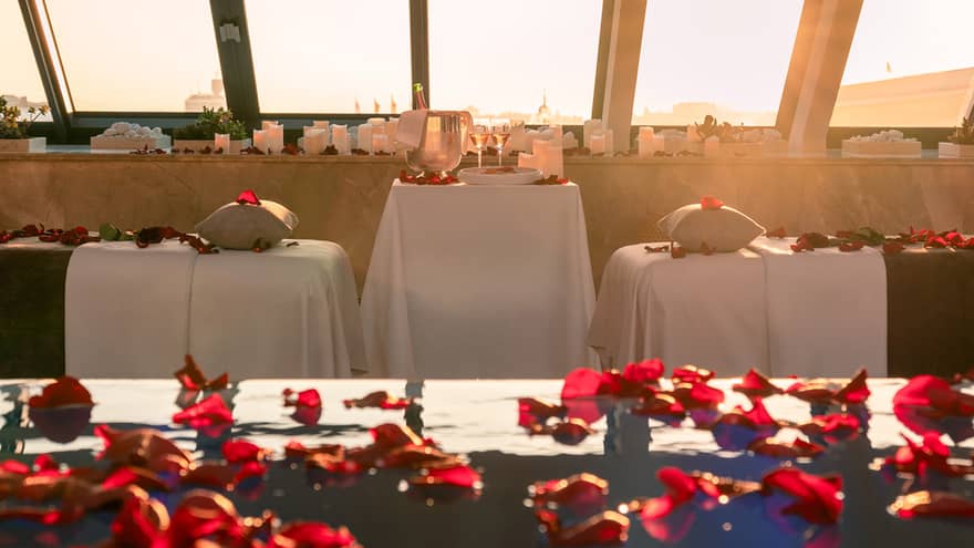 Spa pool sprinkled with red rose petals and couples spa tables poolside with skylight views