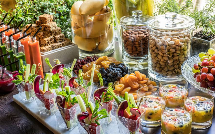 A buffet spread for a coffee break, complete with nuts, fruit, crudités and sweets