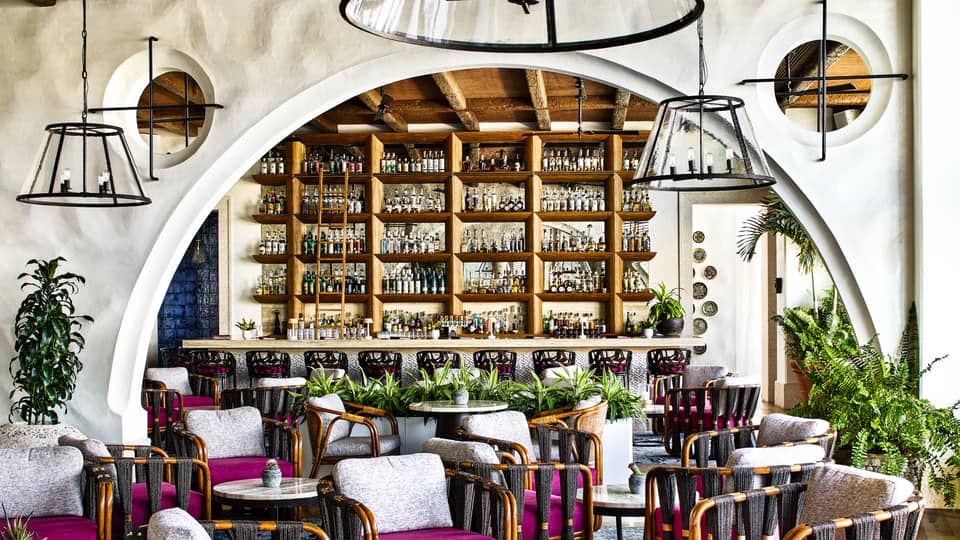 Restaurant with curved archway, various arm chairs with magenta seat cushions and white back cushions