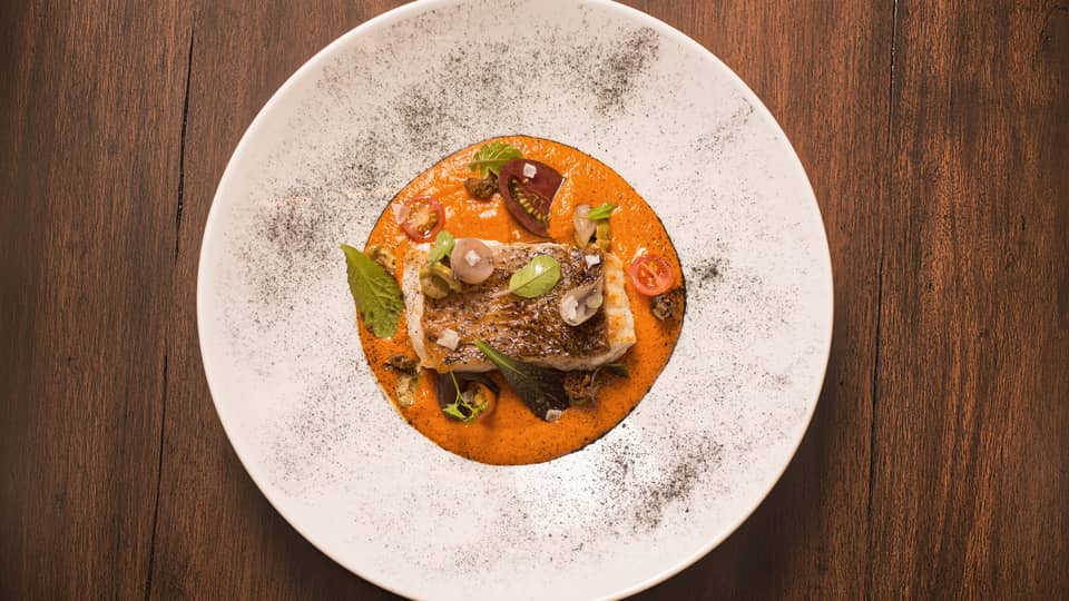 Tomato risotto topped with a piece of grilled fish