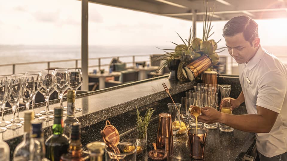 Man makes cocktails behind bar on a boat