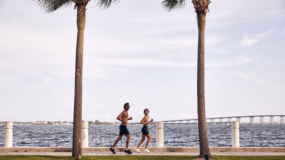 Man and woman running on sidewalk next to water