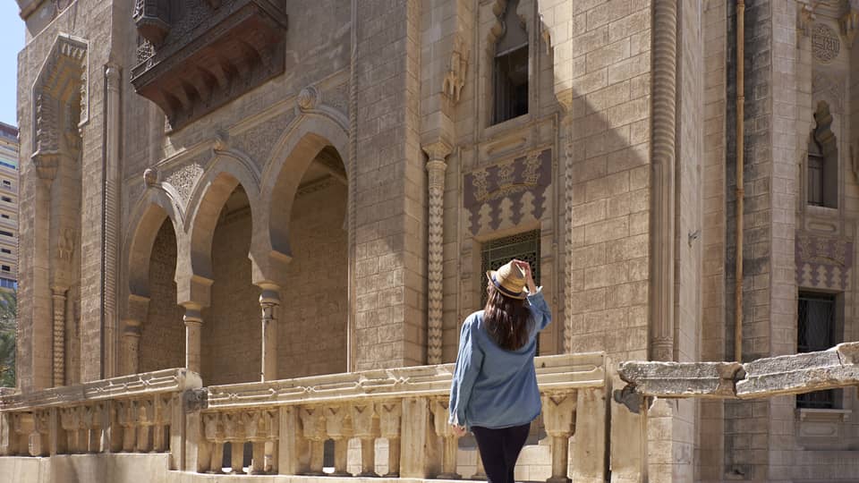 Woman looks up at historic palace exterior in Alexandria, Egypt