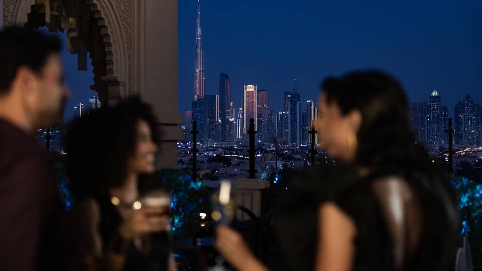 Friends mingle at a Dubai hotel rooftop bar with Dubai skyline view