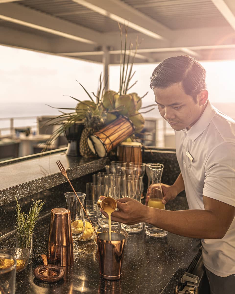Man makes cocktails behind bar on a boat