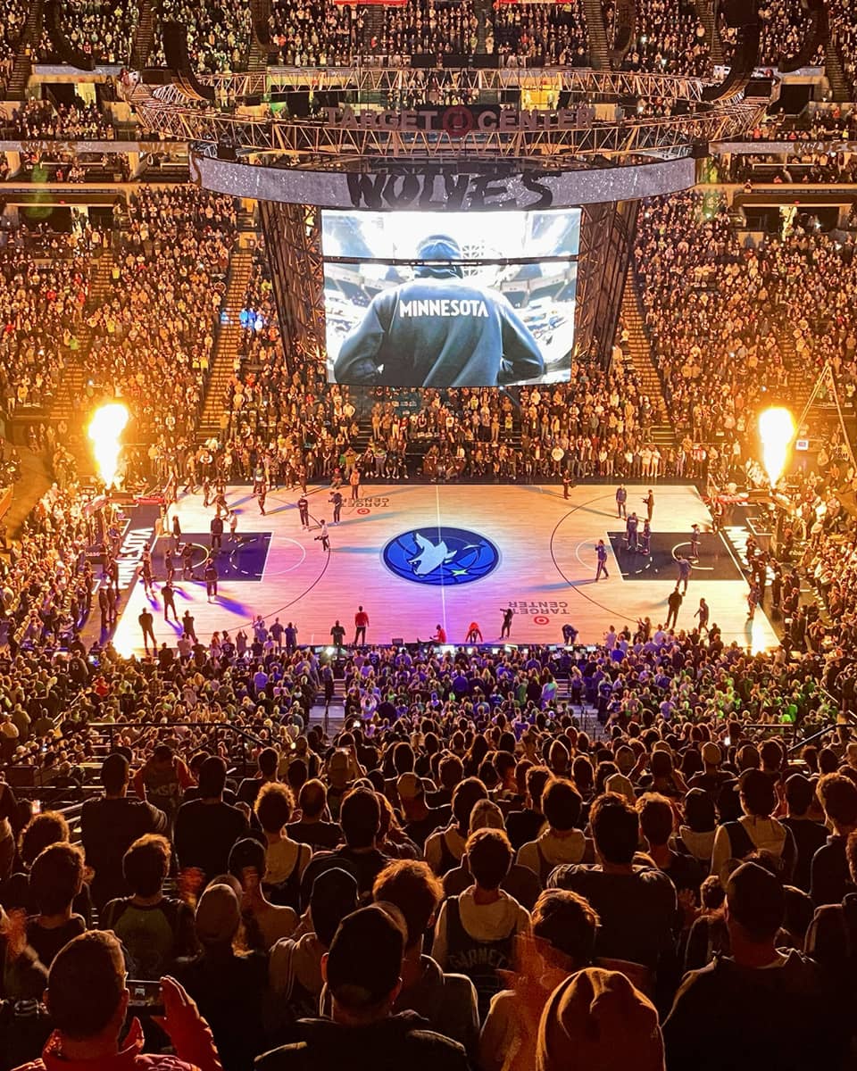 Large audience watching a basketball game with purple lights on the basketball court.