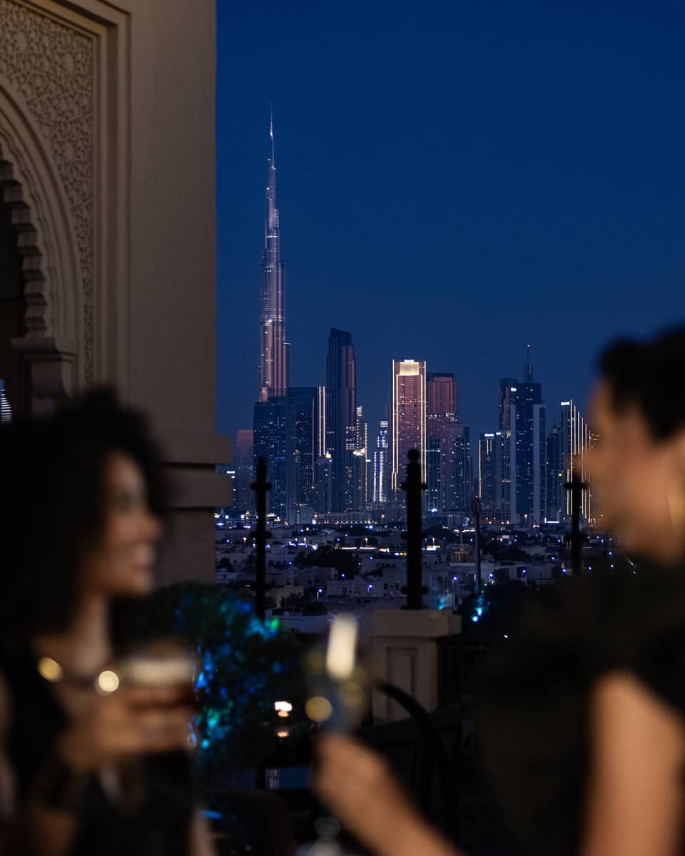 Friends mingle at a Dubai hotel rooftop bar with Dubai skyline view