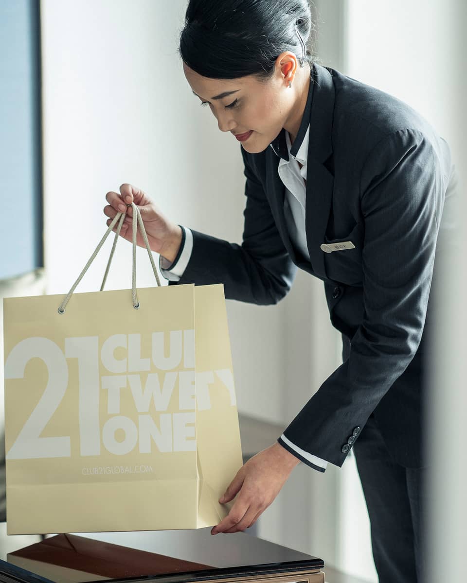Hotel staff pours coffee from carafe into cup on brunch tray on in-room dining table