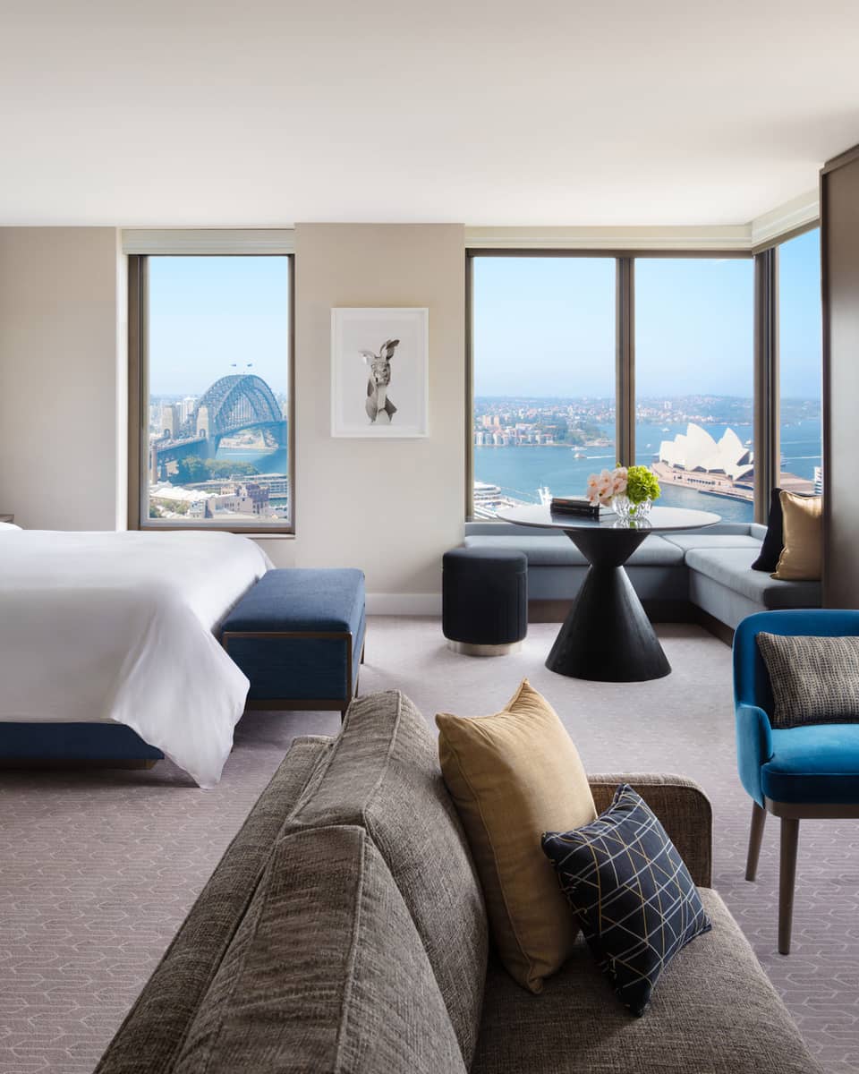 A cozy bedroom with subtle bursts of colourful decor, overlooking the iconic Sydney Harbour