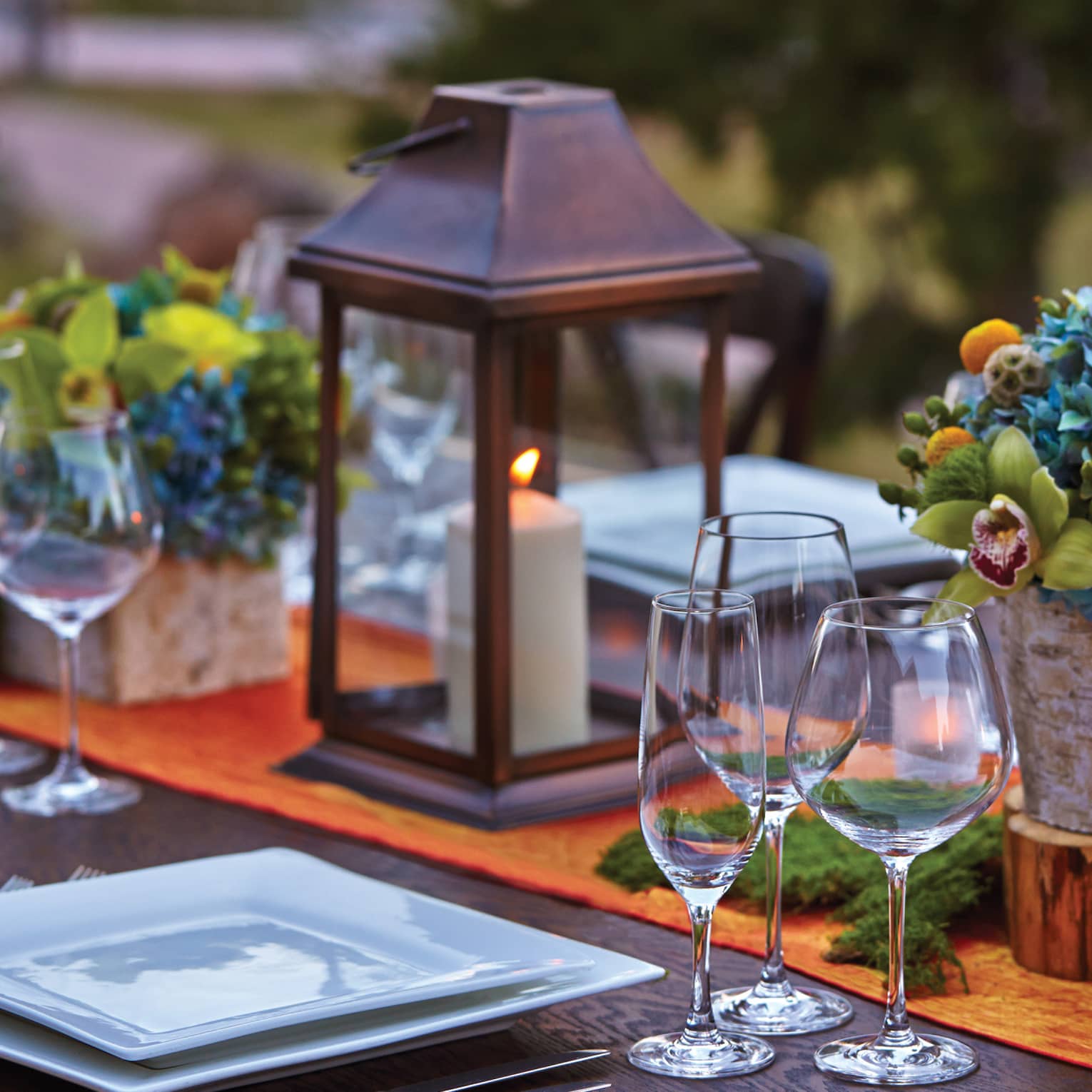 Close-up of lanterns, flowers on patio dining table at sunset